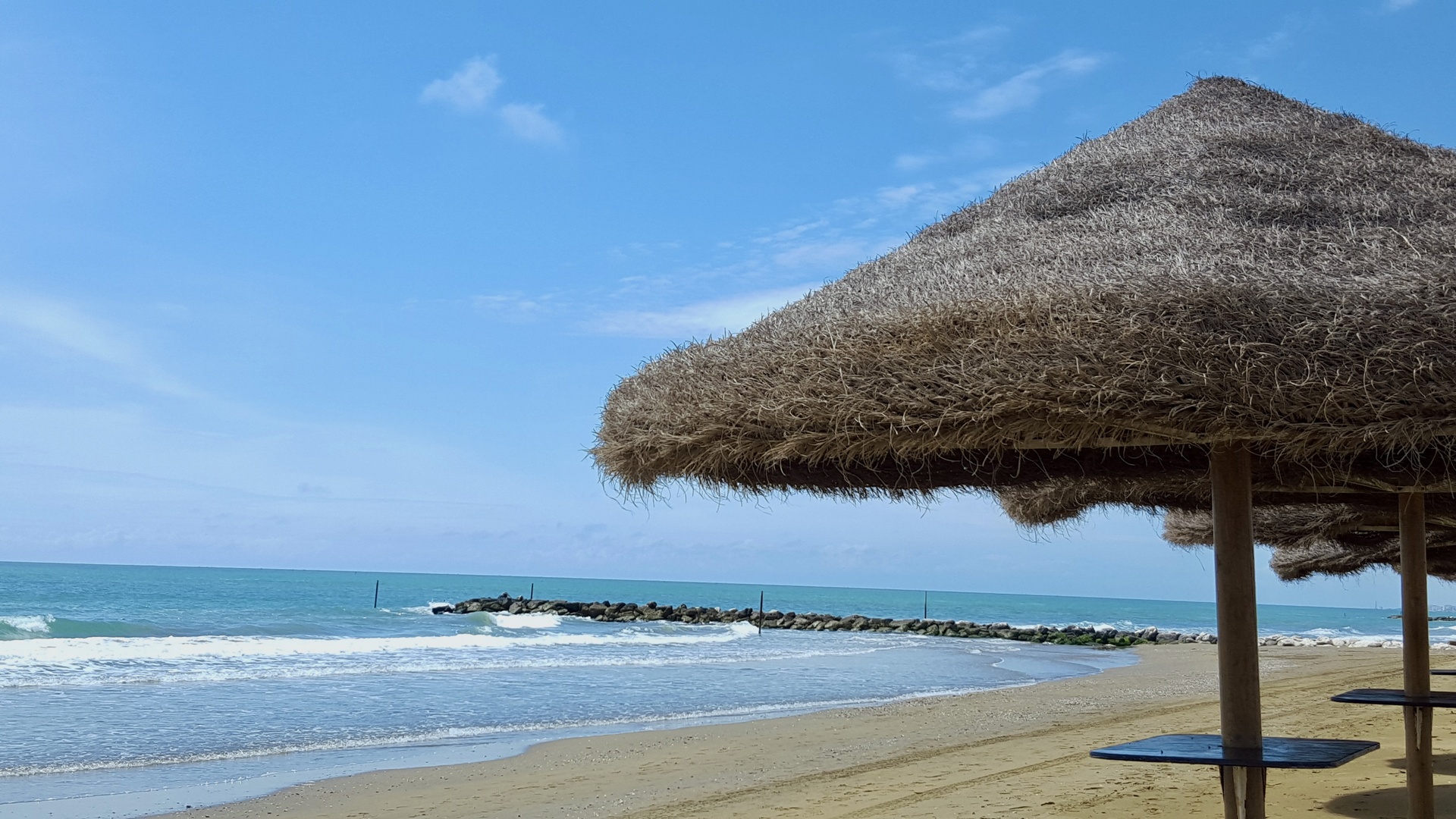 Ombrellone di paglia in prima fila, con la scogliera e il mare aperto